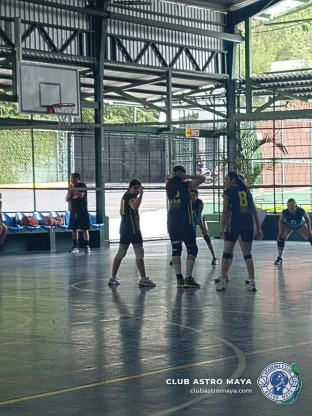 Jugadoras de voleibol del Club Astro Maya en cancha techada durante un partido